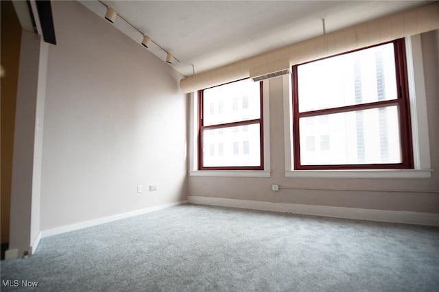 carpeted spare room with rail lighting and baseboards