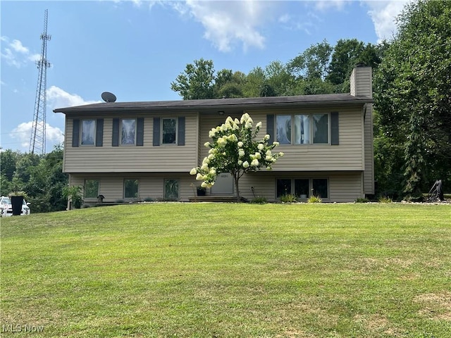 raised ranch with a front lawn and a chimney