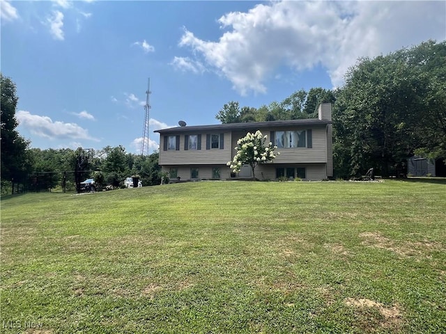 raised ranch featuring a chimney and a front lawn