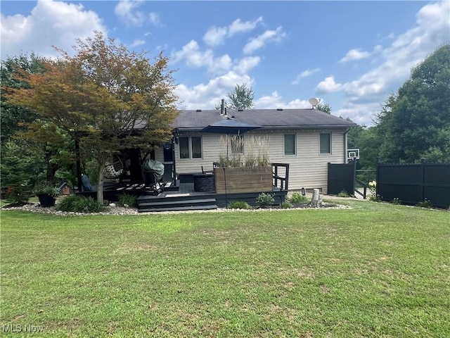 back of property featuring fence, a deck, and a lawn