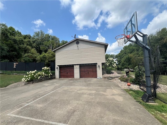 exterior space with a garage, driveway, an outdoor structure, and fence