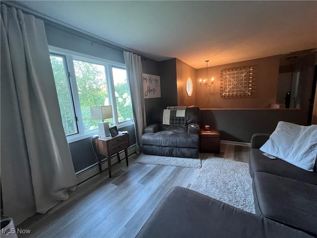 living area with an inviting chandelier, baseboards, a baseboard heating unit, and wood finished floors