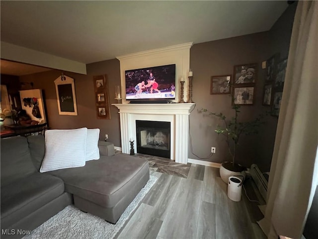 living room with baseboards, a fireplace, baseboard heating, and wood finished floors