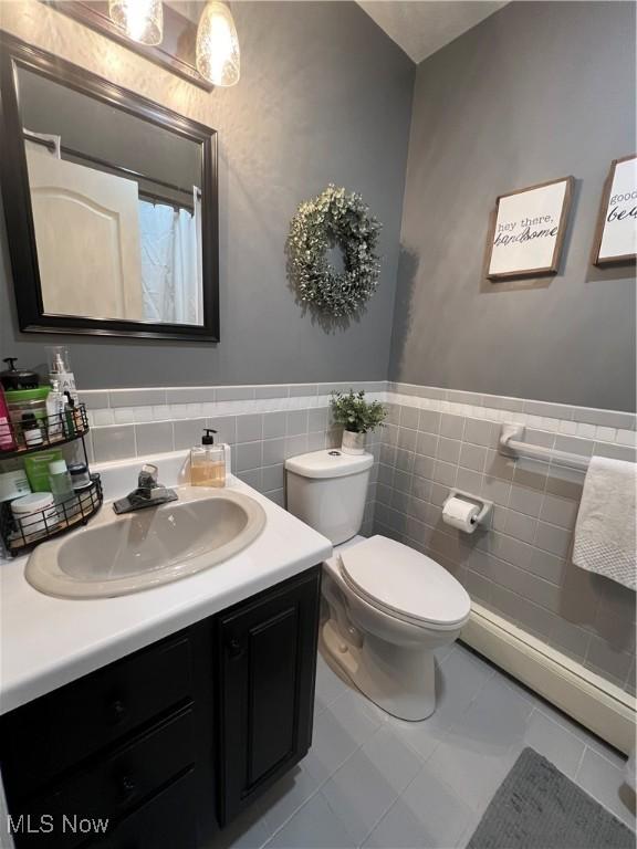 full bath with toilet, a wainscoted wall, vanity, and tile walls