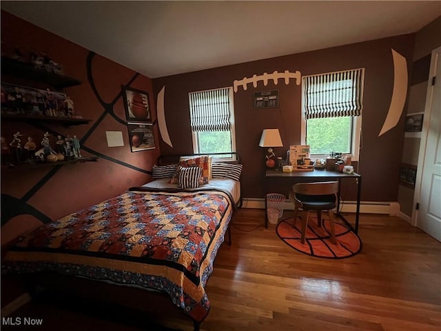 bedroom featuring a baseboard heating unit, baseboards, and wood finished floors