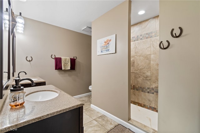 bathroom with vanity, a tile shower, tile patterned flooring, and toilet