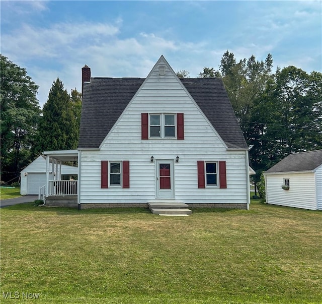 view of front of house with a garage, a front lawn, and an outbuilding