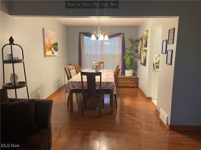 dining space featuring dark wood-type flooring and a notable chandelier