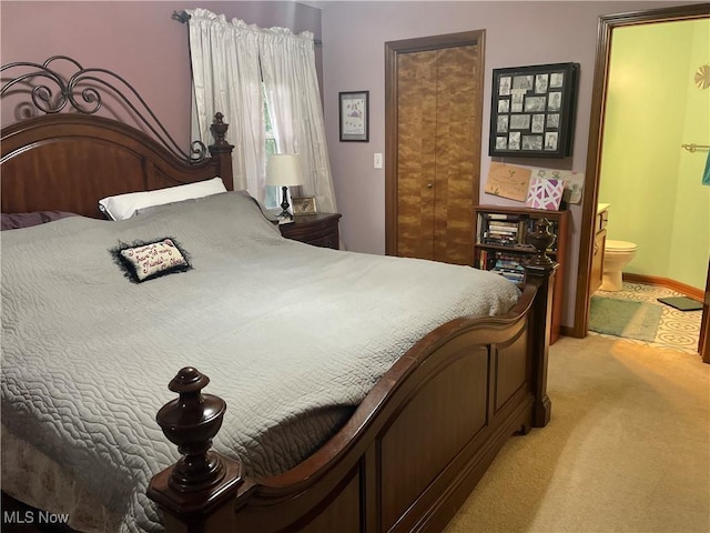 bedroom featuring light colored carpet and ensuite bathroom