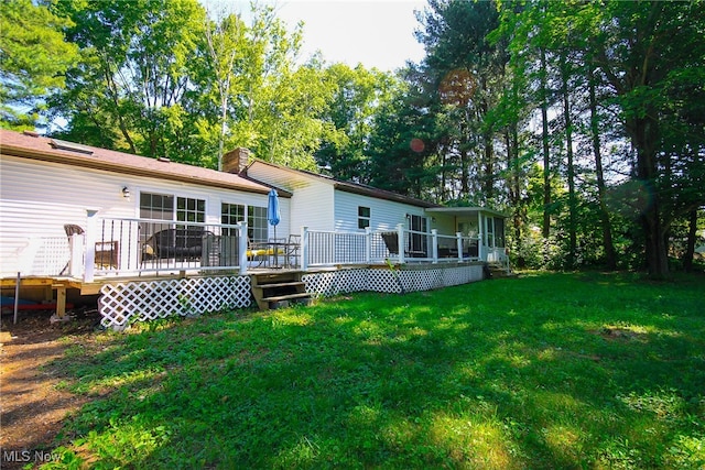 rear view of property with a wooden deck and a yard