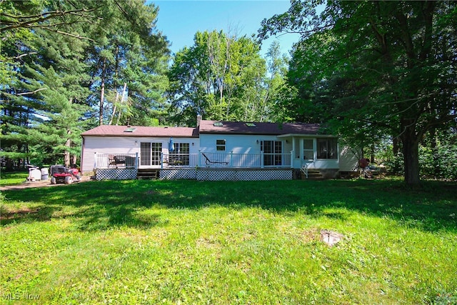 back of house featuring a lawn and a wooden deck