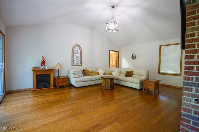 living room with lofted ceiling, wood-type flooring, brick wall, and a fireplace