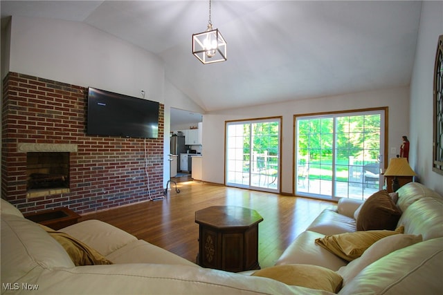 living room with lofted ceiling, a fireplace, an inviting chandelier, and wood-type flooring