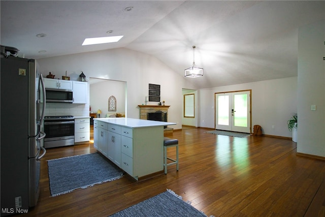 kitchen with backsplash, dark hardwood / wood-style flooring, a kitchen island, stainless steel appliances, and a kitchen breakfast bar