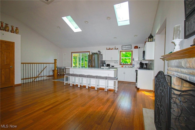 living room with lofted ceiling with skylight, hardwood / wood-style floors, and plenty of natural light