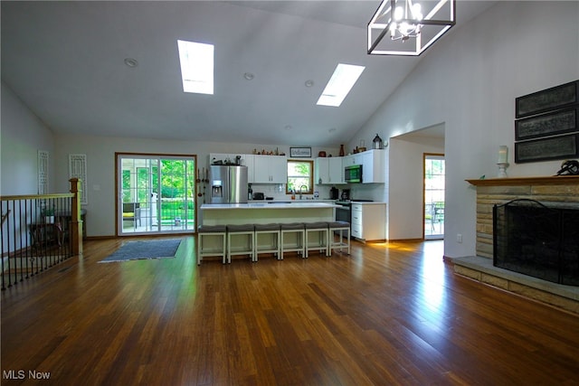 interior space with a healthy amount of sunlight, dark wood-type flooring, a notable chandelier, and a skylight