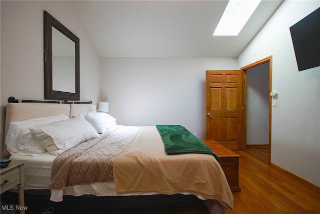 bedroom with wood-type flooring and vaulted ceiling with skylight