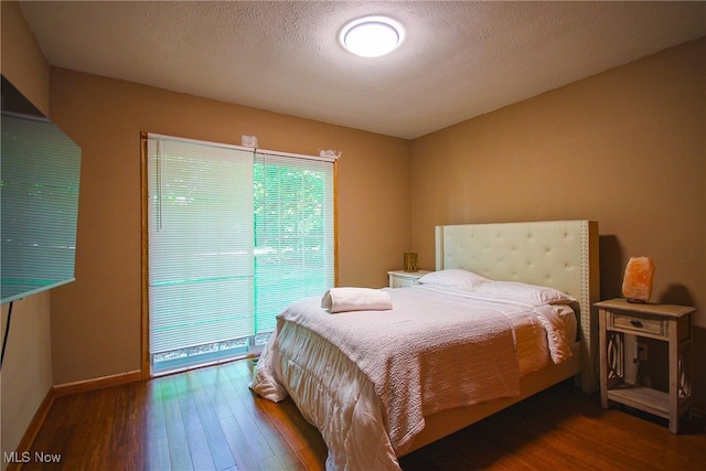 bedroom featuring wood-type flooring, access to outside, and a textured ceiling