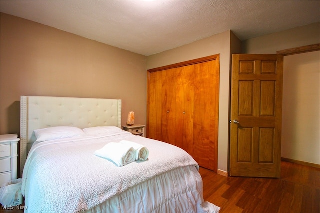 bedroom featuring dark hardwood / wood-style flooring, a closet, and a textured ceiling