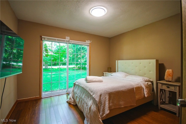 bedroom with multiple windows, access to outside, and hardwood / wood-style flooring