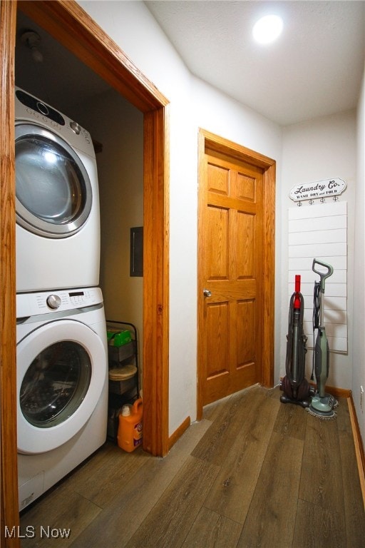 laundry room with stacked washer and clothes dryer and dark hardwood / wood-style flooring