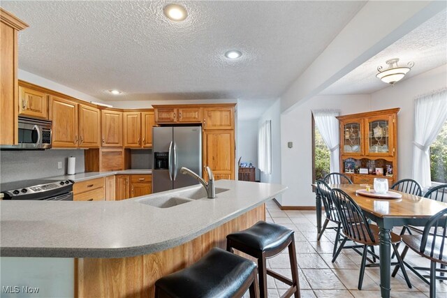 kitchen featuring light tile patterned flooring, stainless steel appliances, a wealth of natural light, and a breakfast bar