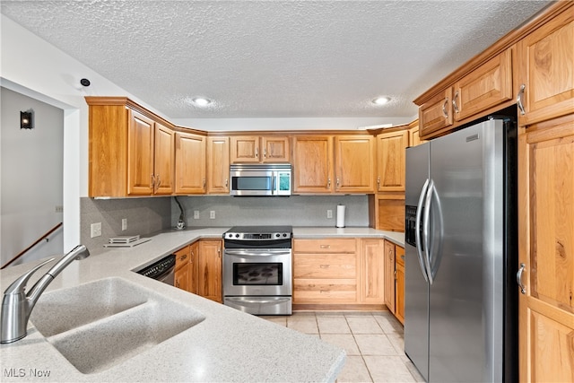 kitchen with tasteful backsplash, stainless steel appliances, sink, light tile patterned floors, and a textured ceiling