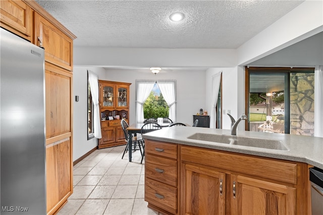 kitchen with appliances with stainless steel finishes, a textured ceiling, light tile patterned floors, and sink