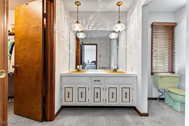 bathroom with dual vanity, toilet, and a textured ceiling