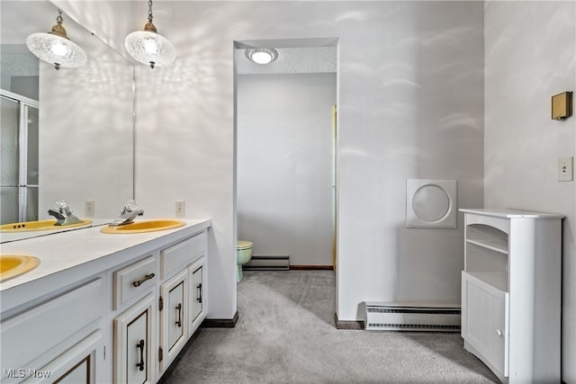 bathroom with toilet, baseboard heating, and double vanity