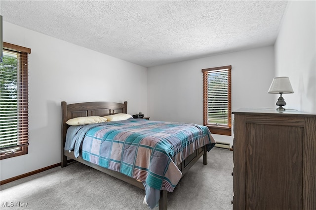 carpeted bedroom with baseboard heating and a textured ceiling