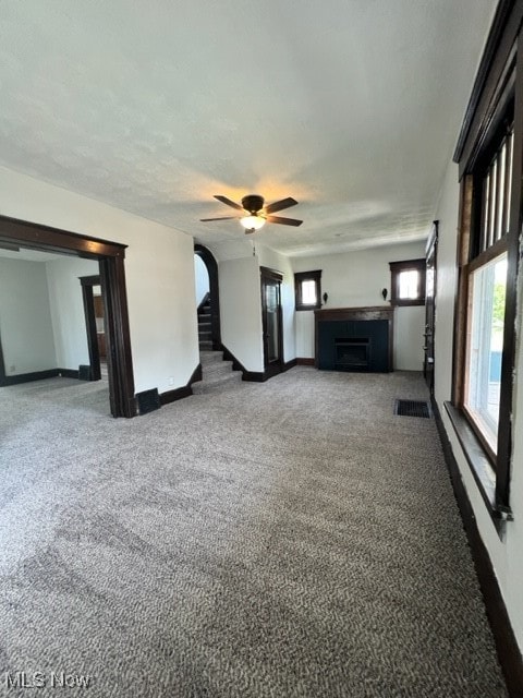 unfurnished living room featuring light colored carpet and ceiling fan