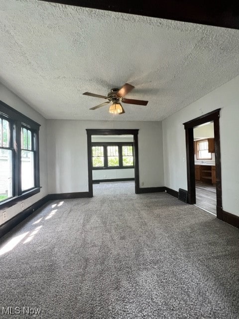 carpeted spare room with a textured ceiling and ceiling fan