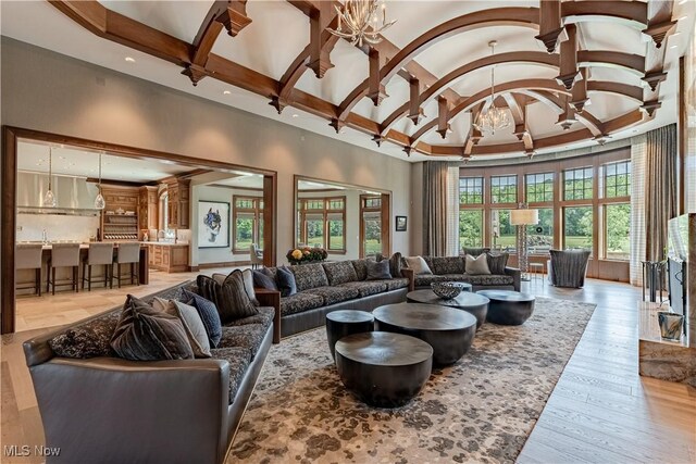 living room with light hardwood / wood-style flooring, high vaulted ceiling, beamed ceiling, and an inviting chandelier