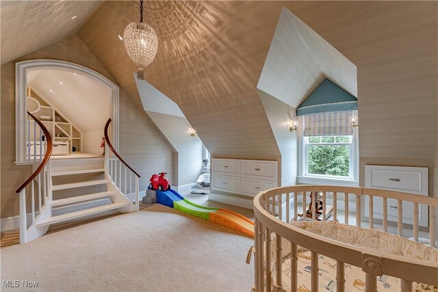 carpeted bedroom featuring an inviting chandelier and vaulted ceiling