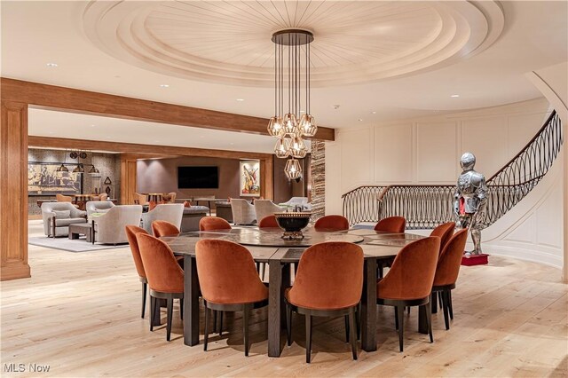 dining room featuring light hardwood / wood-style floors, an inviting chandelier, and a raised ceiling