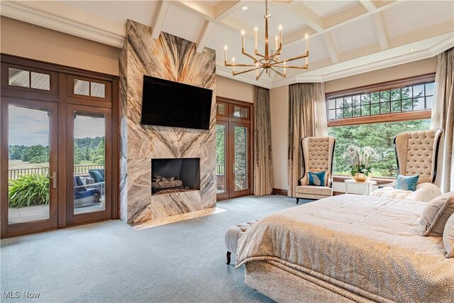 carpeted bedroom with french doors, an inviting chandelier, a fireplace, and access to exterior