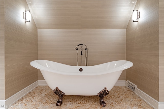 bathroom featuring lofted ceiling and a tub