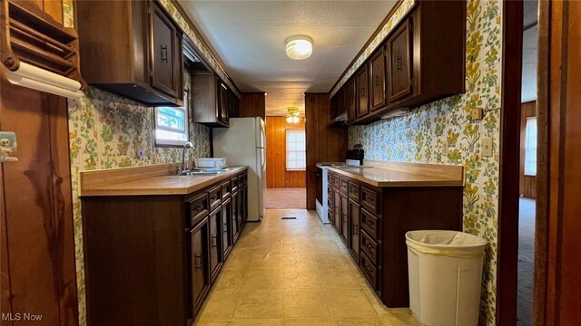 kitchen with sink, fridge, light tile patterned floors, dark brown cabinetry, and ceiling fan