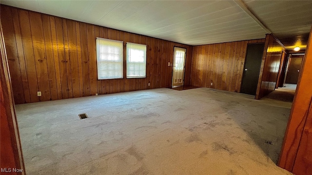 carpeted empty room with wood walls