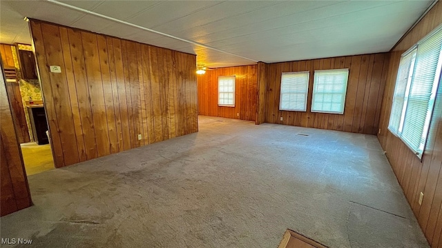 spare room with plenty of natural light, wood walls, and light carpet