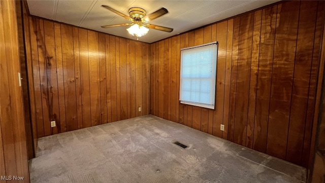 carpeted spare room with wooden walls and ceiling fan