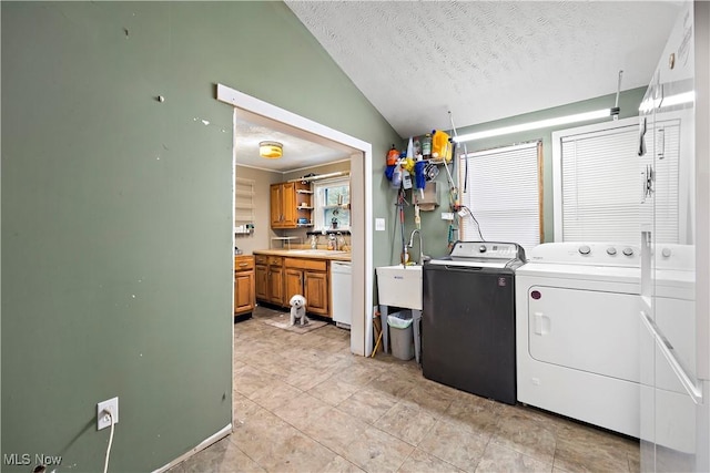 laundry area with sink, light tile patterned flooring, a textured ceiling, and independent washer and dryer