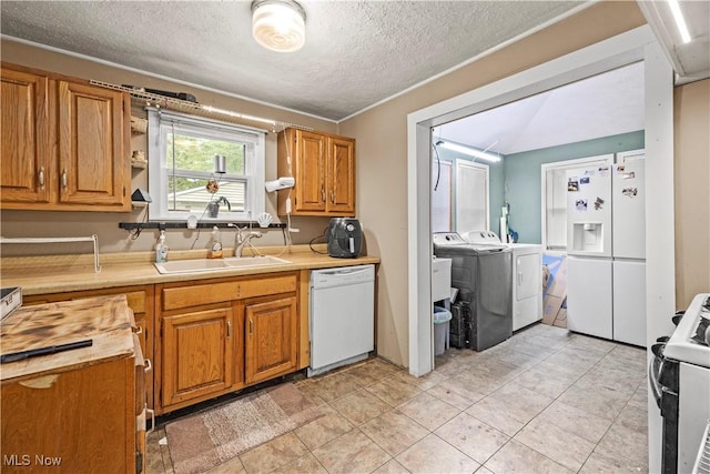 kitchen with white appliances, sink, washer and dryer, a textured ceiling, and light tile patterned flooring