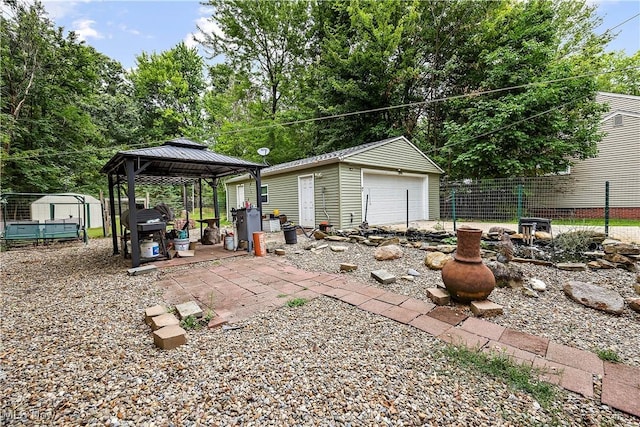 view of yard featuring a gazebo, a storage unit, and a garage