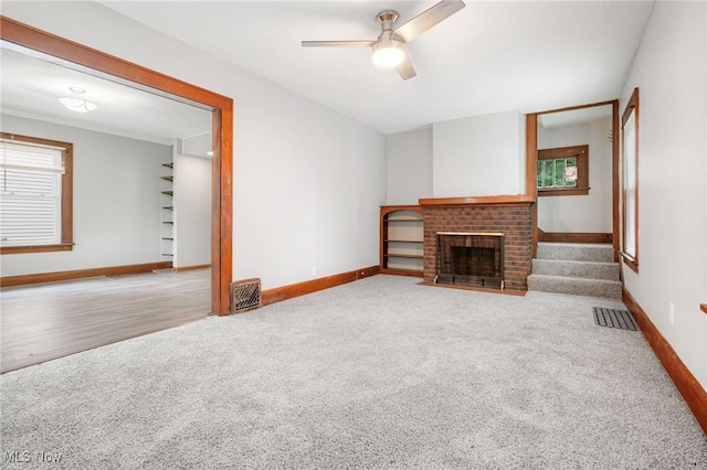 unfurnished living room featuring a fireplace, light colored carpet, and ceiling fan