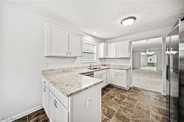 kitchen featuring white cabinets, sink, hanging light fixtures, light stone countertops, and a chandelier