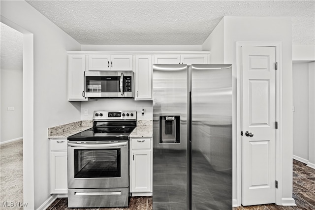 kitchen with a textured ceiling, white cabinetry, stainless steel appliances, and light stone counters