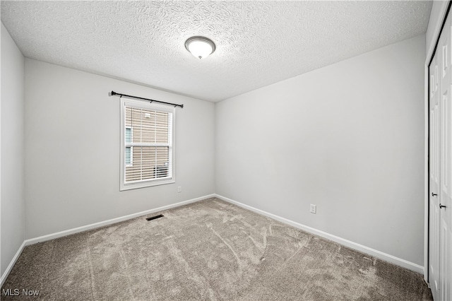 unfurnished room with carpet flooring and a textured ceiling