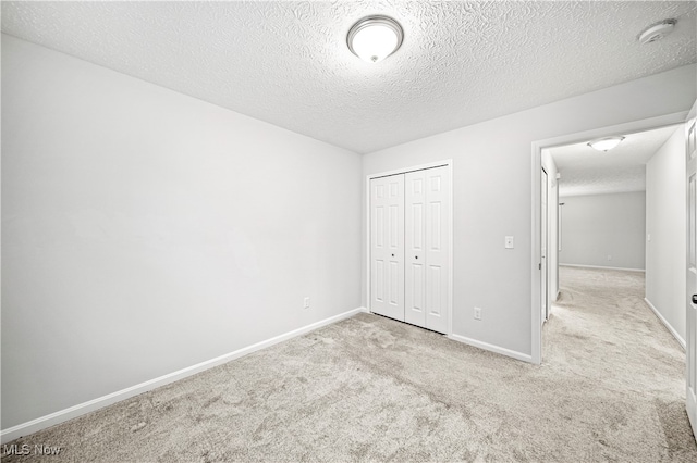 unfurnished bedroom with a textured ceiling, light colored carpet, and a closet